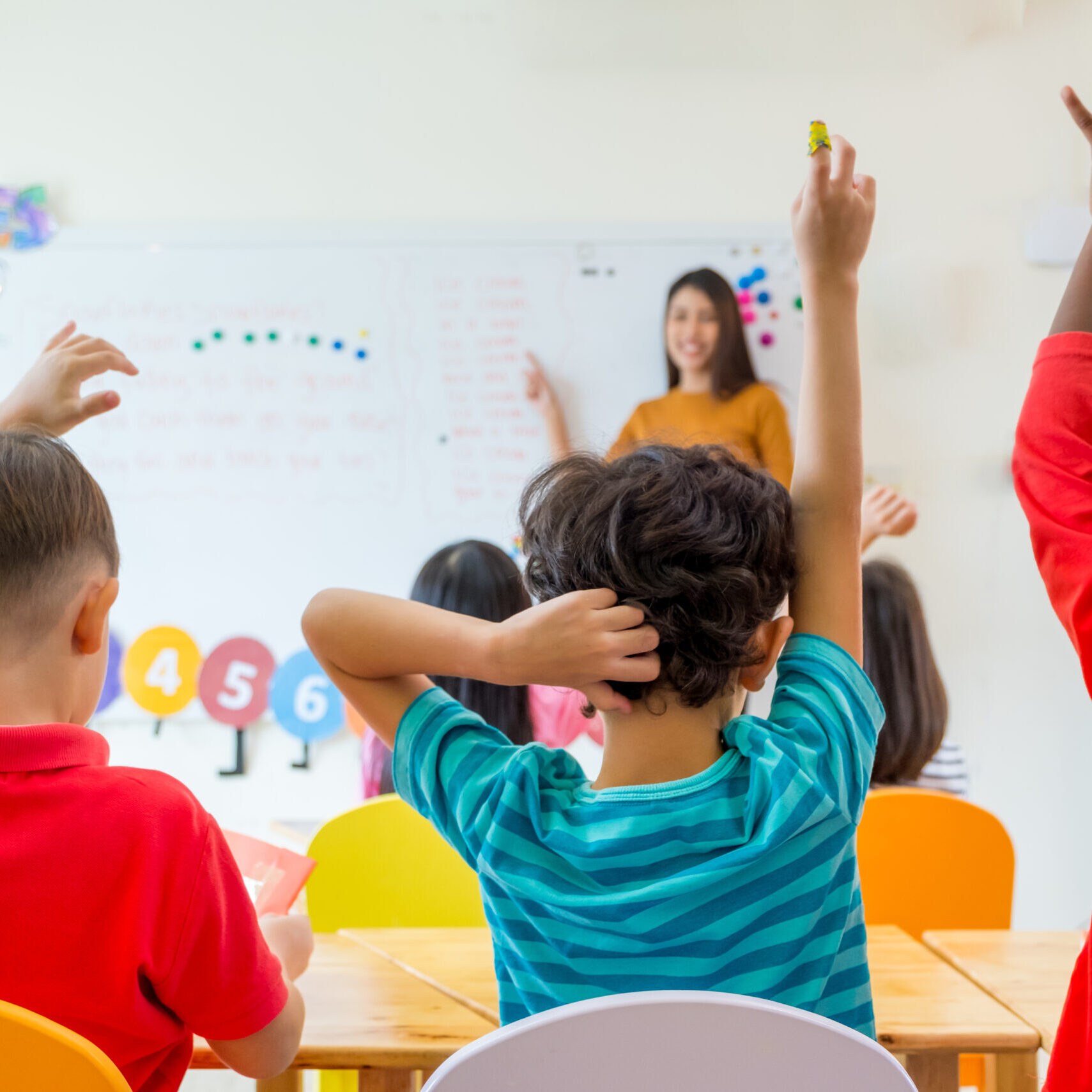 LRCE- Students in Classroom - Raising Hands.jpg Young students raise their hands during a classroom lesson as a smiling teacher leads from the front. The colorful and interactive setting reflects the vibrant learning environments shaped by LRCE-trained educators.