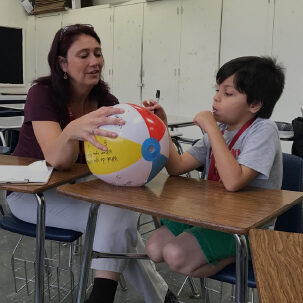 LRCE-Teacher-with-Student LRCE Teacher 1-on-1 session with student, showing him writing on beach ball