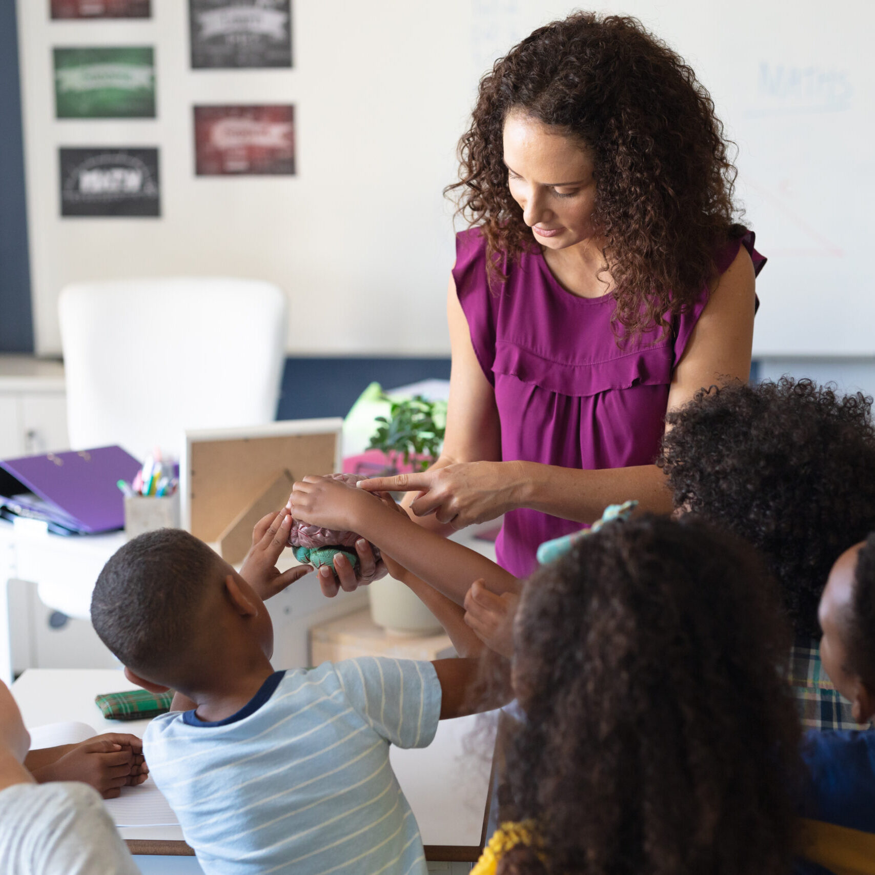 Teacher showing model of human brain to students A teacher holds a model of the human brain while engaging a group of curious students gathered around her. The hands-on science lesson reflects the interactive and inclusive approach of LRCE-trained educators.
