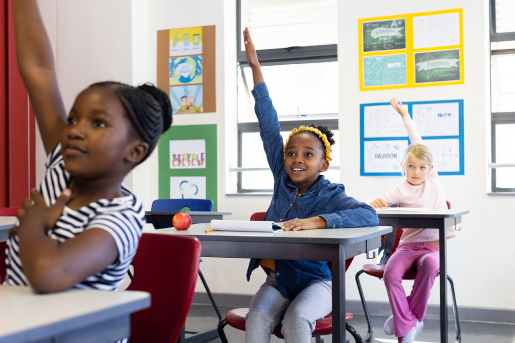 "Engaged elementary students raising hands in a diverse Louisiana classroom, supported by LRCE-trained educators.
